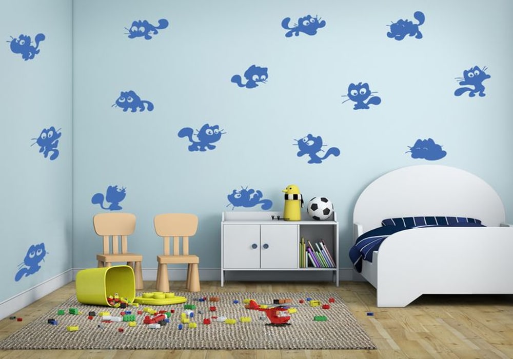 A children's bedroom with blue walls decorated with multiple blue cat stickers